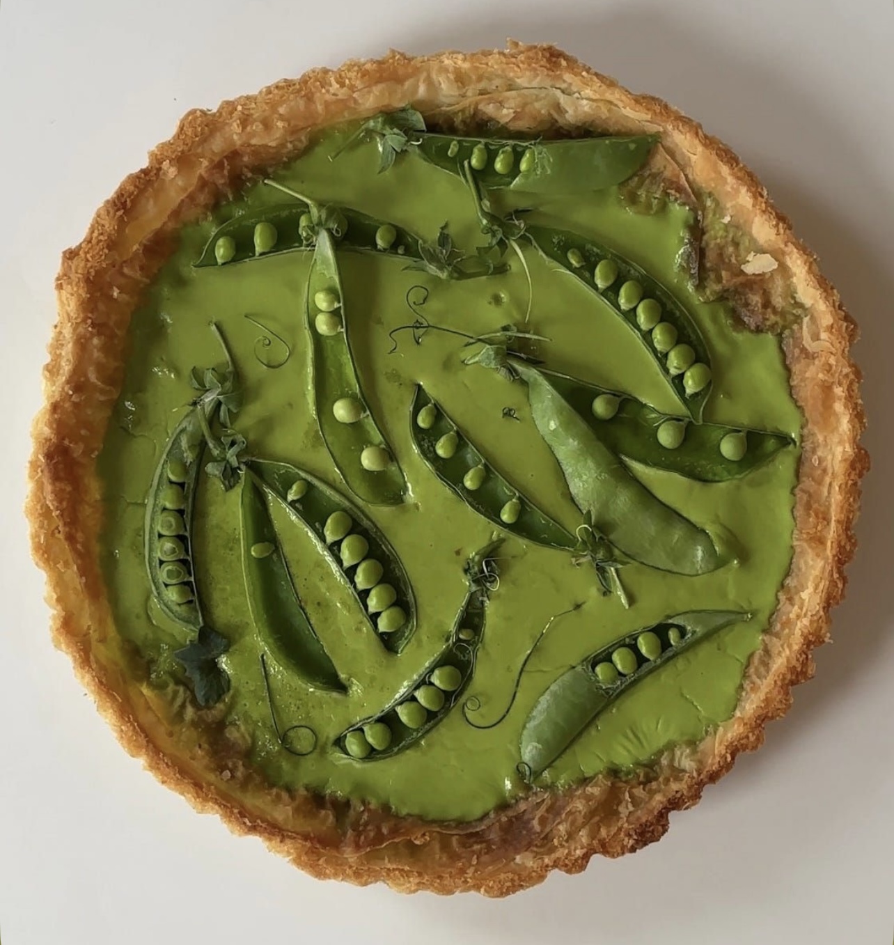 Versgebakken broodjes met boter, jam en thee op een houten tafel.