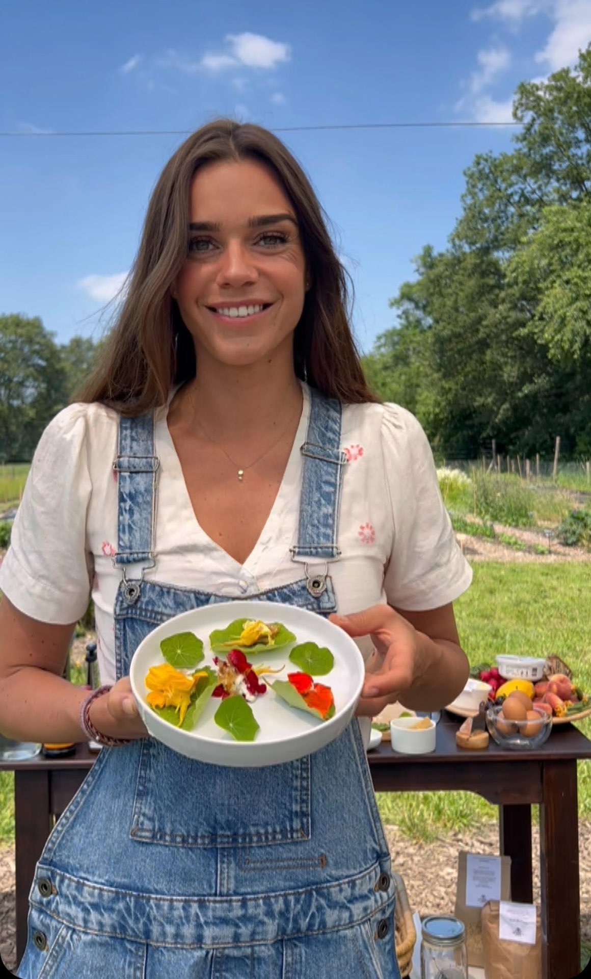 Claudia, oprichter van De Landschapskeuken, met een schaal eetbare bloemen en bladeren in een zelfoogsttuin